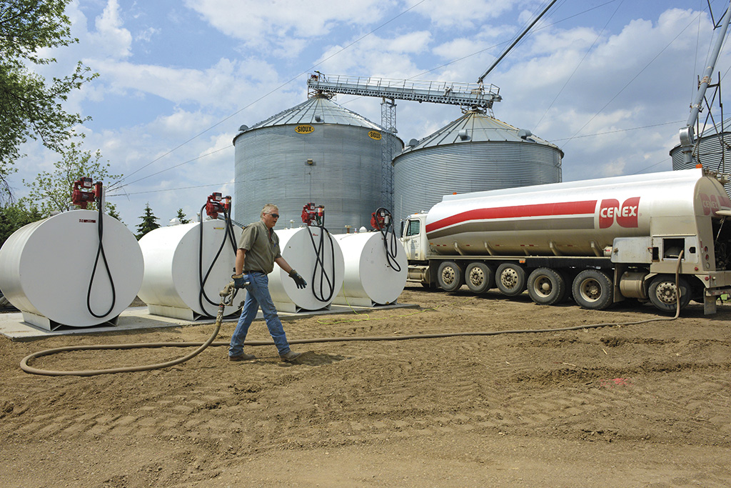 Man walking towards propane tanks with propane truck hose