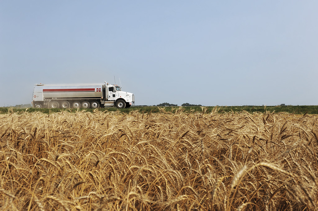 Cenex propane truck driving down a rural road between two wheat fields