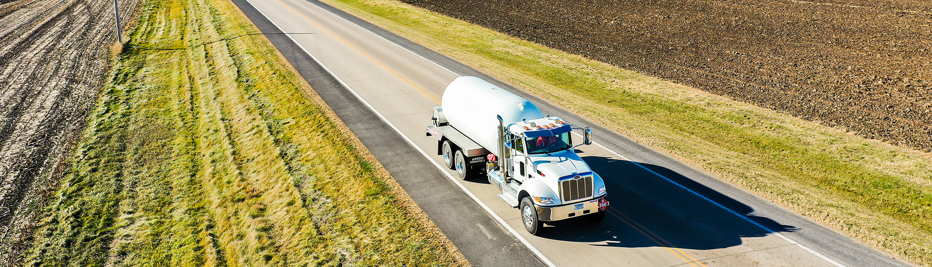 Propane truck on open road between two fields